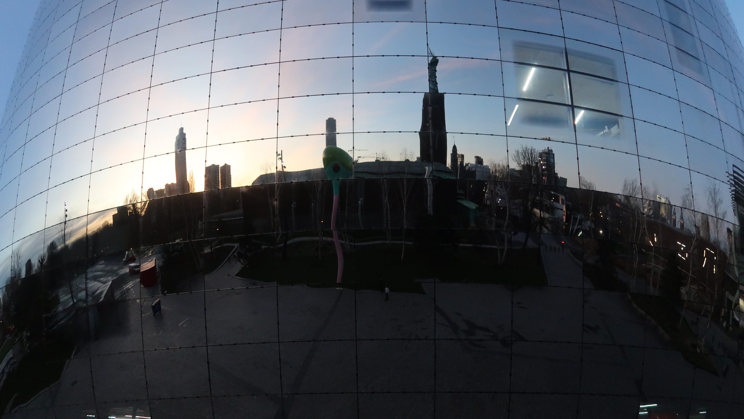 A cityscape is reflected in a bulbous mirrored building